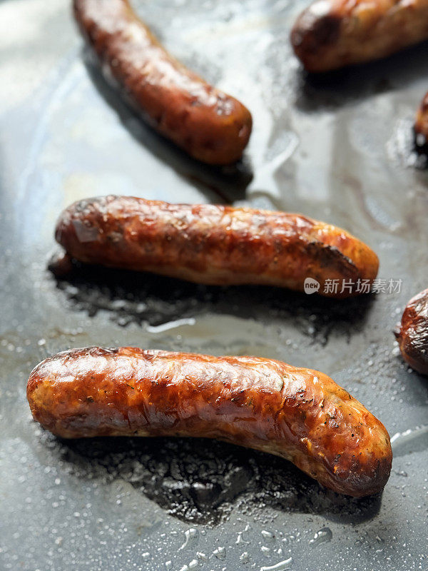 Close-up image of rows of grilled pork sausages on hotel self service breakfast buffet metal serving tray, elevated view, focus on foreground